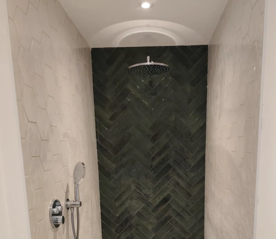 Renovated shower with green herringbone tiles and white walls